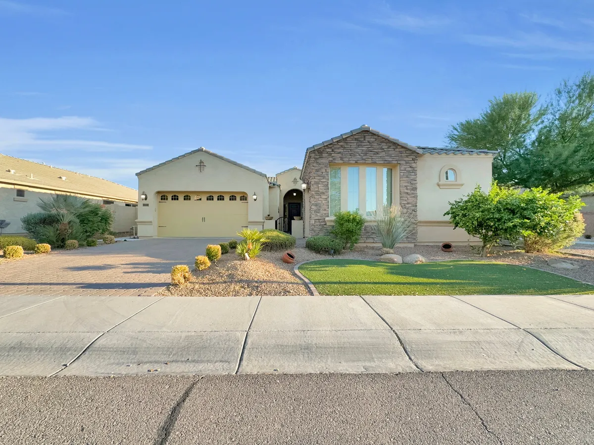 This exterior photo highlights the home's inviting front porch, attractive stonework facade, and well-kept green lawn. The scene radiates a welcoming, tranquil atmosphere, perfect for appreciating sunsets and relaxing outdoors.
