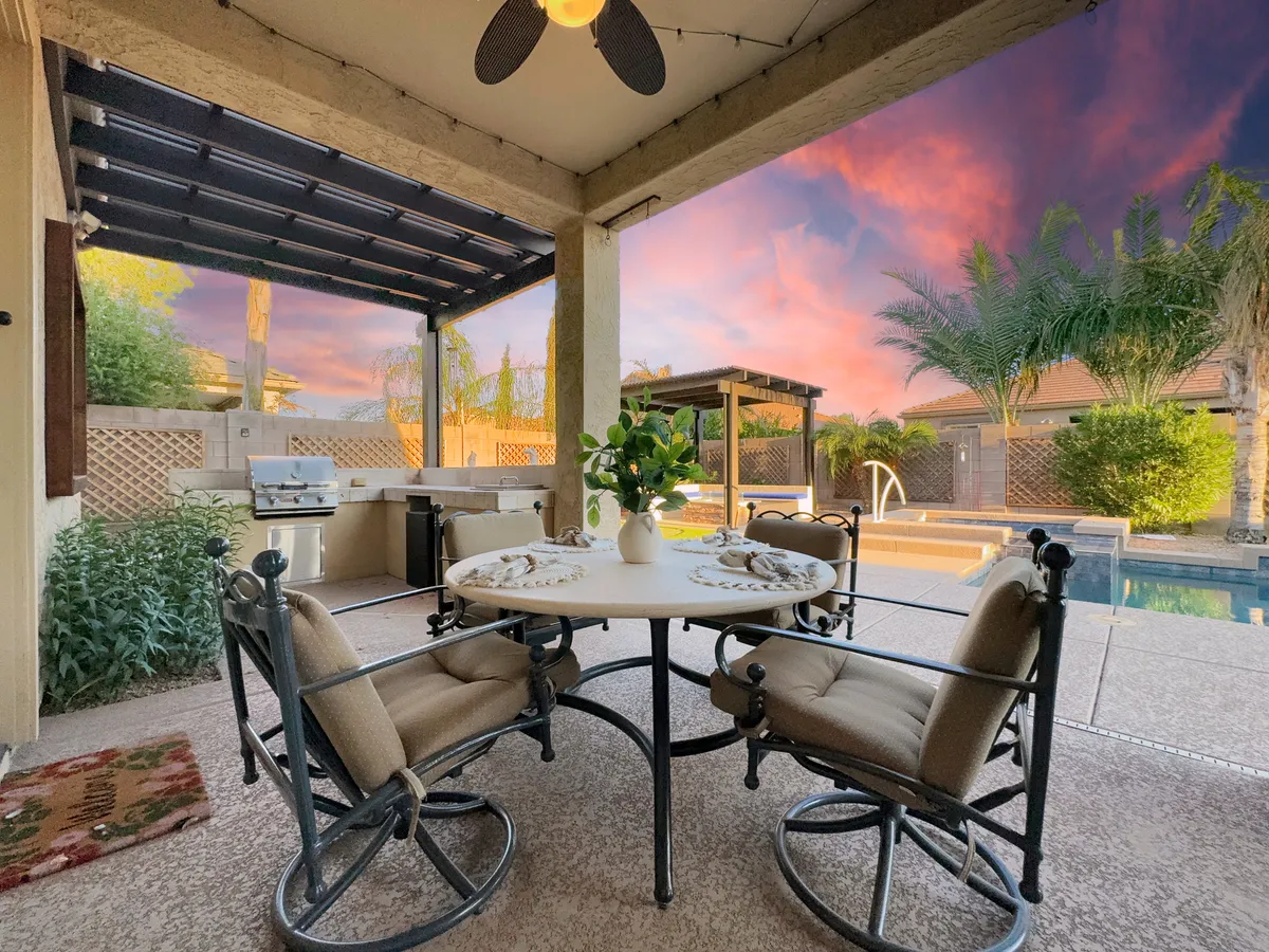 A tranquil outdoor dining area with a table adorned with a floral centerpiece overlooking the swimming pool. An outdoor grill is also visible, suggesting opportunities for al fresco meals and gatherings.