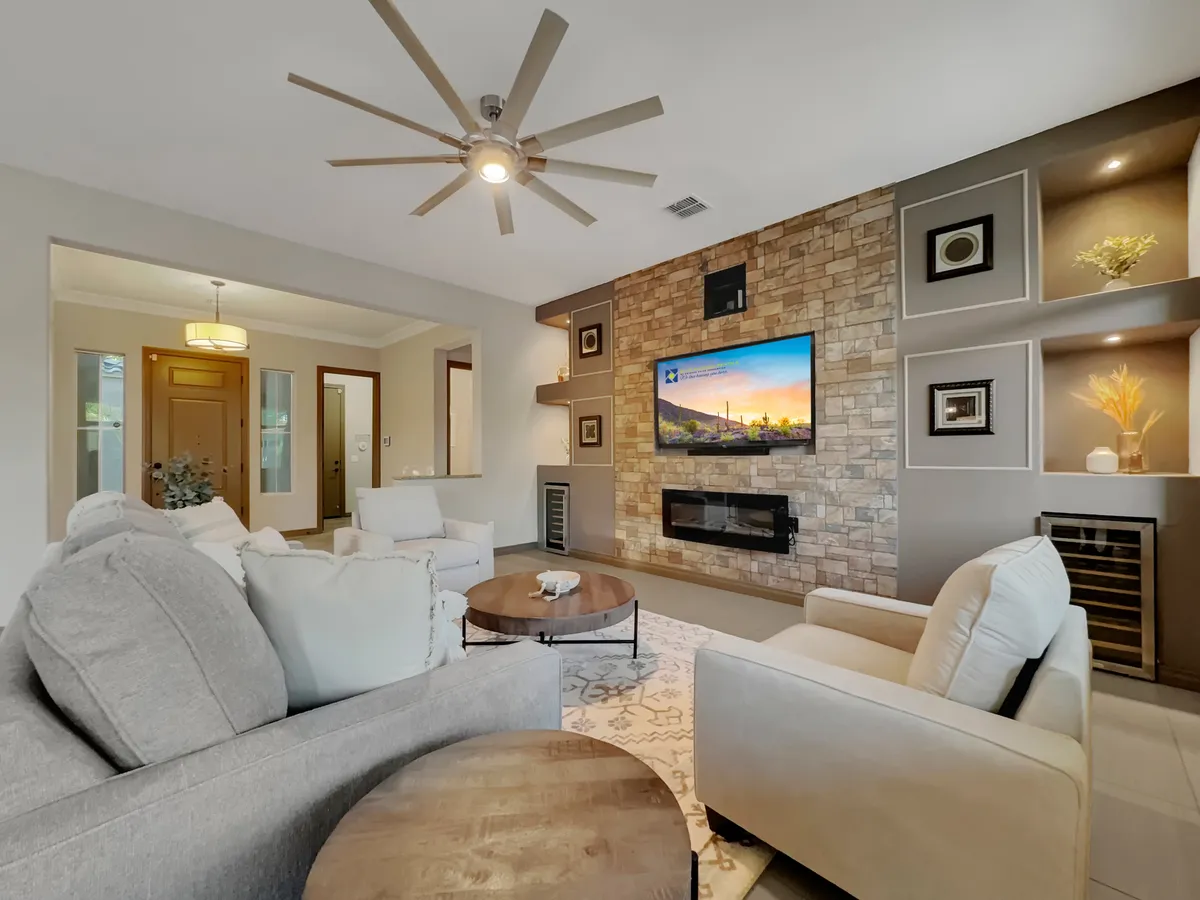 This modern living area includes a stone feature wall, television, comfortable seating, and a view that hints at sunset enjoyment. The cozy setup is ideal for evening relaxation after a day of exploring or lounging by the pool.