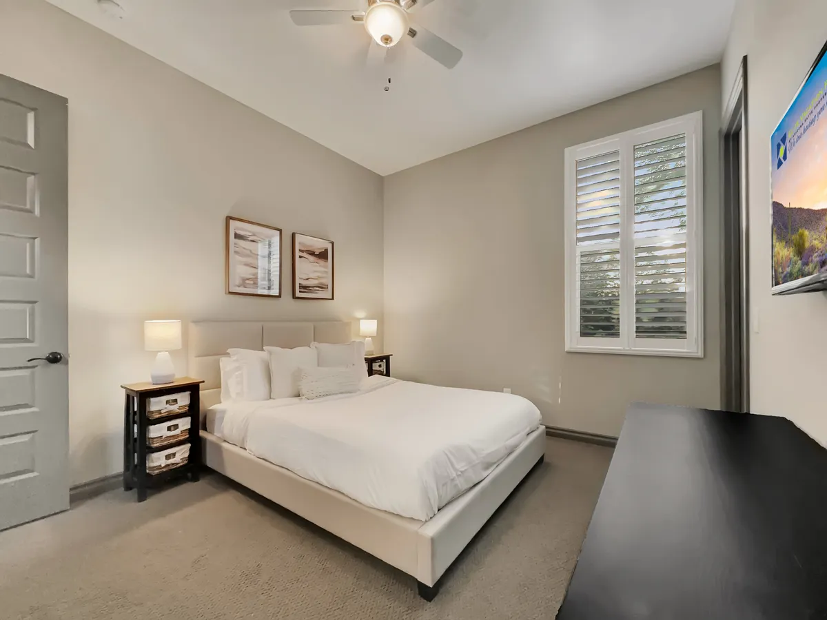 A tranquil bonus room with a cozy bed, wall art, nightstands, and a television, blending restful comfort with flexible function for reading, relaxation, or use as an extra sleeping space.